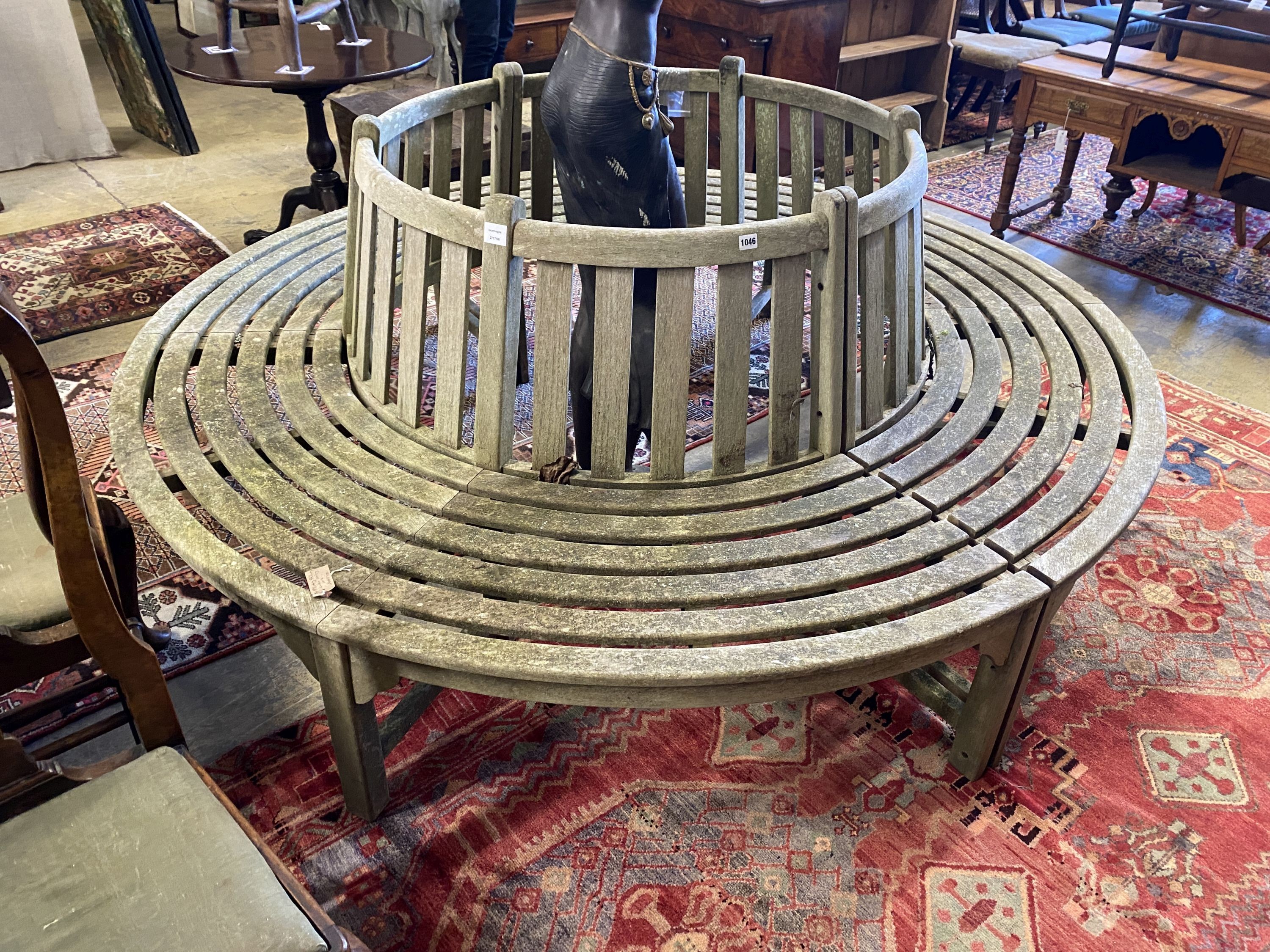 A weathered teak sectional circular garden tree seat, aperture approx. 106cm, seat diameter 220cm, height 88cm